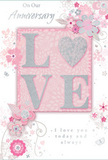 A romantic anniversary card is depicted in close detail, its design a gentle celebration of enduring love in a palette of pastel pinks and silvery greys, much like the soft tones of an English spring morning in Milton Keynes. At the centre of the card, the word LOVE stands proudly in raised, glitter-dusted lettering, the shimmering texture catching the light and adding a sense of luxury and touchable charm. The letter O is transformed into a graceful heart, filled with silver sparkle, making it the emotional focal point of the design, as captivating as the heart of a carefully crafted bouquet. Surrounding this central word, delicate blossoms in blush, mauve, and pale ivory unfurl with a watercolor softness, their edges slightly blurred as though brushed by hand. Fine swirling lines, tiny petals, and discreet butterflies weave among the blooms, adding movement and a hint of whimsy, reminiscent of a tranquil garden walk near Willen Lake. The background remains a gentle pink wash, offering a calm canvas that allows the floral detailing to shine without overwhelming the eye. In graceful, understated script, the phrases On Our Anniversary and I love you today and always appear, positioned to balance the flowers and central motif, echoing the sentiment of long-lasting partnership. The overall composition feels like a keepsake designed to accompany a hand-delivered arrangement from a local Milton Keynes florist, a quiet yet deeply heartfelt tribute to years of shared memories and affection.